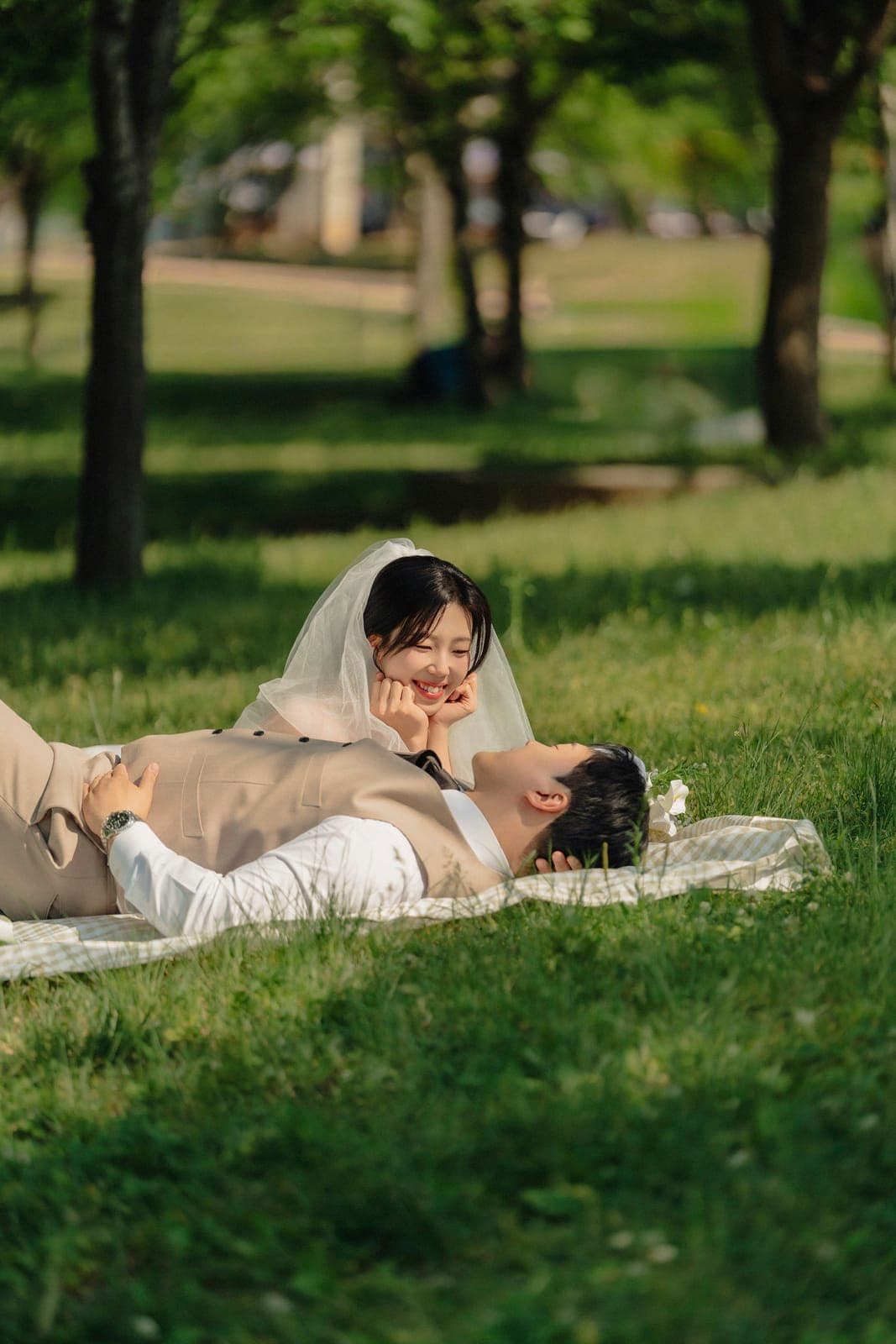 잔디밭 돗자리에 누워 마주 보는 두 사람